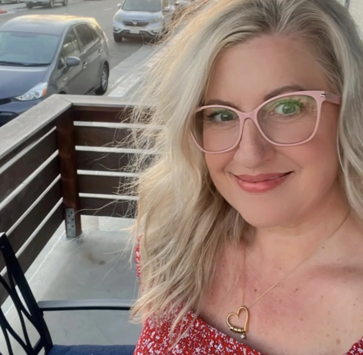 Stacey smiling outdoors in pink glasses